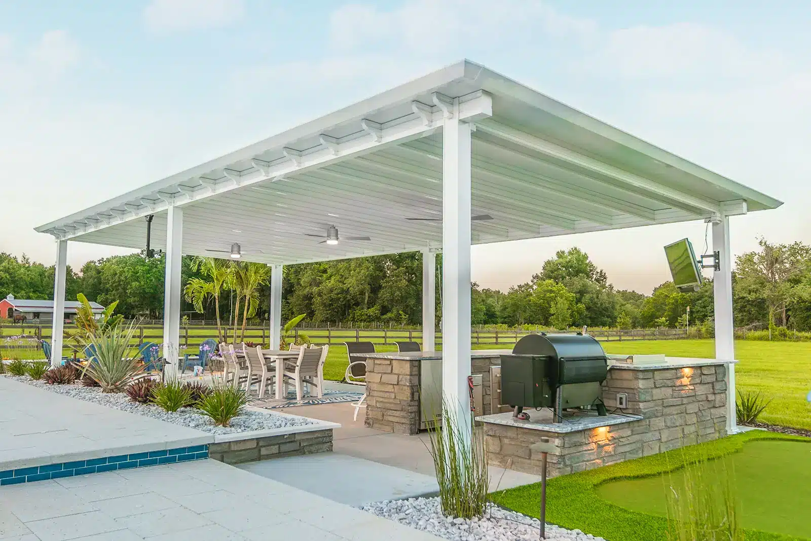 Modern outdoor kitchen and dining area under a louvered pergola