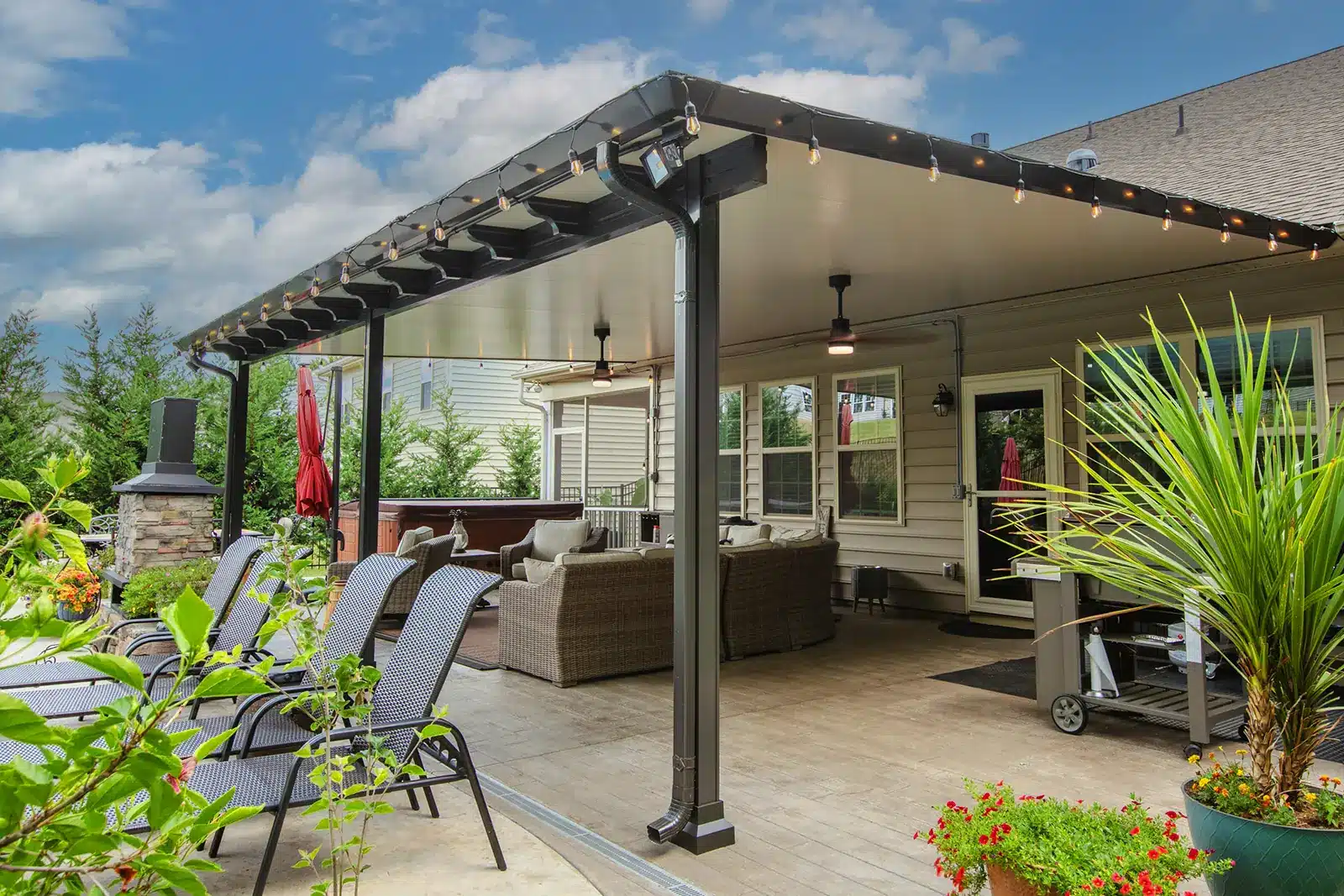Backyard dining and lounge area with fireplace and modern black pergola with recessed lighting